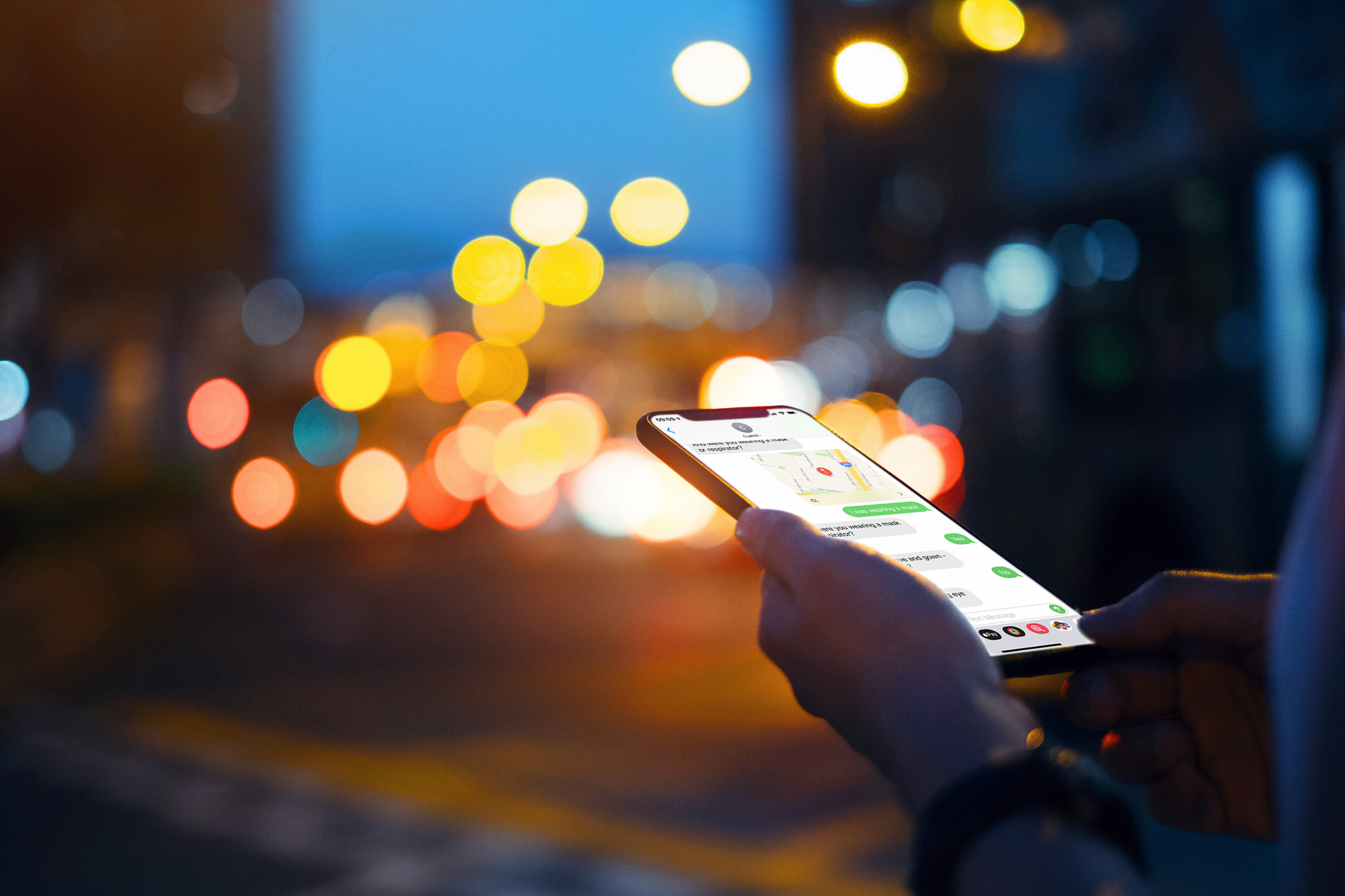 A person holding smartphone with various chart, blurred city lights in the background